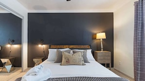 Une chambre d’hôtel avec un lit, des oreillers, une table de chevet, une lampe, une serviette et un tapis à motifs.