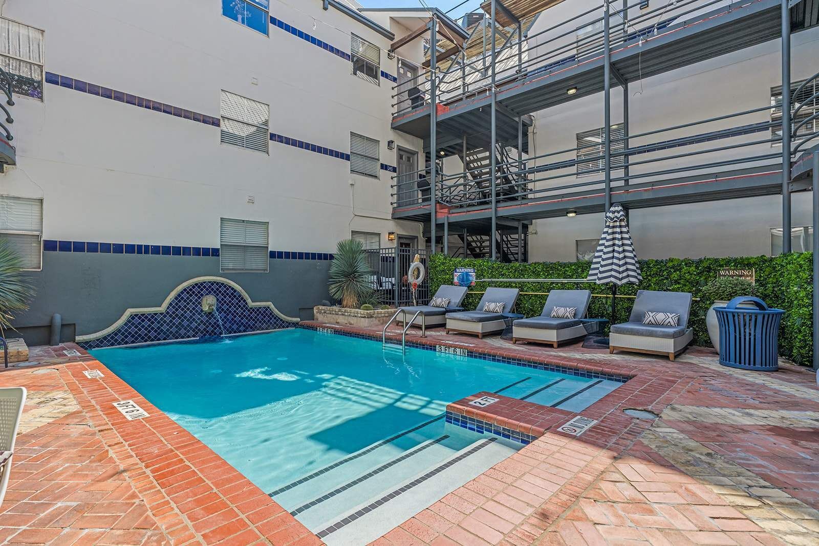 A swimming pool with lounge chairs and a safety sign.