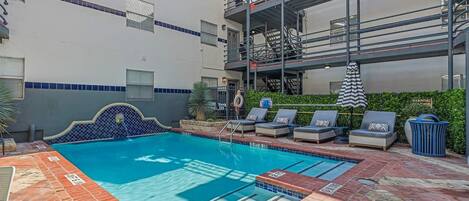 A swimming pool with lounge chairs and a safety sign.