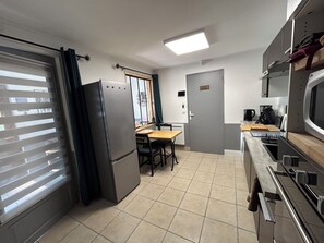 Eine kompakte Küche mit Kühlschrank, Herd, Mikrowelle und einem Essbereich mit Tisch und Stühlen.