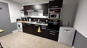 Eine kompakte Küche mit Waschmaschine, Mikrowelle und kleinem Kühlschrank.