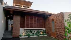 A modern house with a brick exterior, a wooden door, and a small garden area.