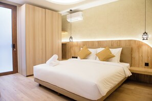 Ein modernes Hotelzimmer mit einem großen Bett, einem Holz-Kopfteil und einer Schiebetür.