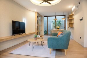 A modern living room with a flat-screen TV, a sofa, a coffee table, and a dining area. - Cozy Mezzanine Loft Bedroom and Master Suite with Shared Pool & Co-Work Deck (badung)