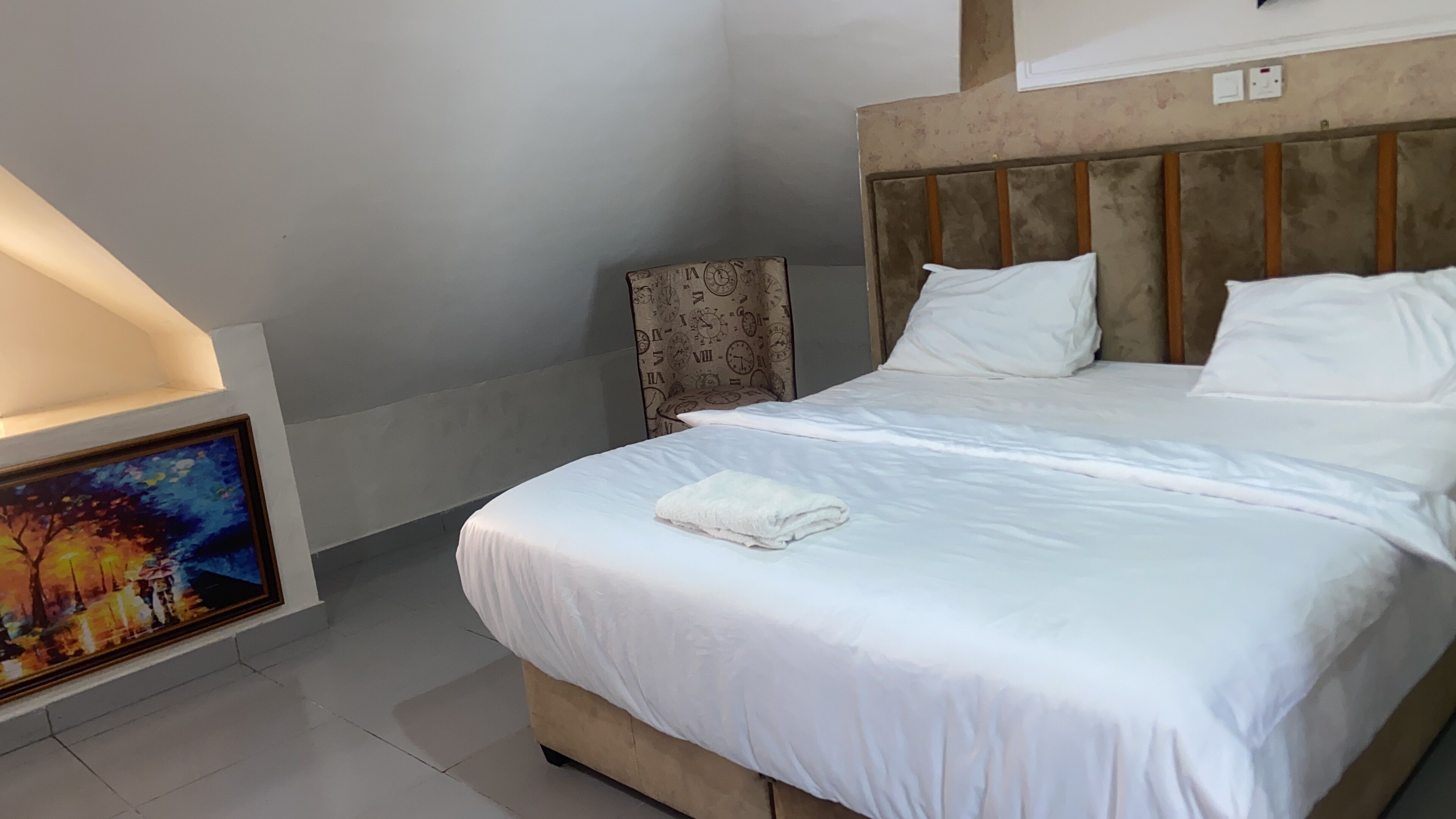 Een hotelkamer met een bed, een schilderij aan de muur en een hoofdeinde.