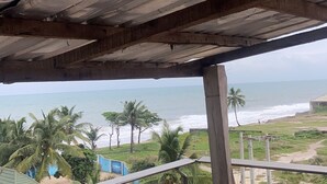 A view from under a wooden structure with a beach and palm trees in the background. - Wimpy hotel and suite beachfront (Lekki)
