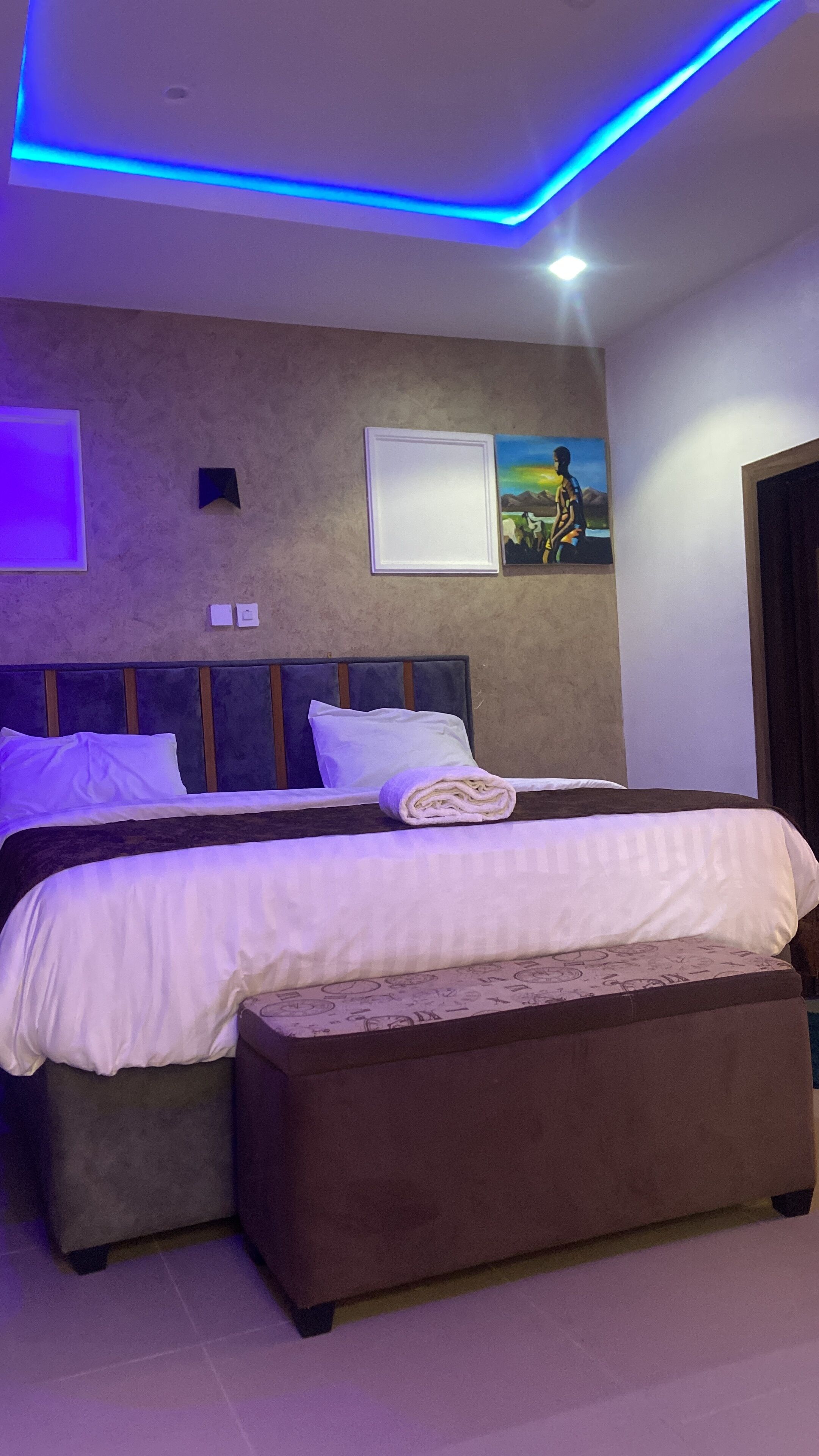 A modern bedroom with a double bed, a bench, and a wall-mounted TV.