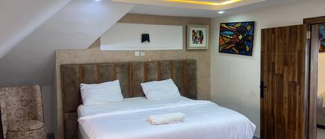 A bedroom with a bed, a headboard, a wall-mounted artwork, and a wooden wardrobe.