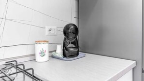 Eine moderne Küche mit Kaffeemaschine, einer dekorativen Tasse und einem Stapel weißer Tassen auf einem Tablett.