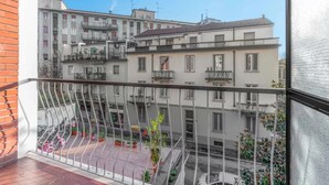 Ein Balkon mit Metallgeländer und Blick auf eine Straße mit Gebäuden.