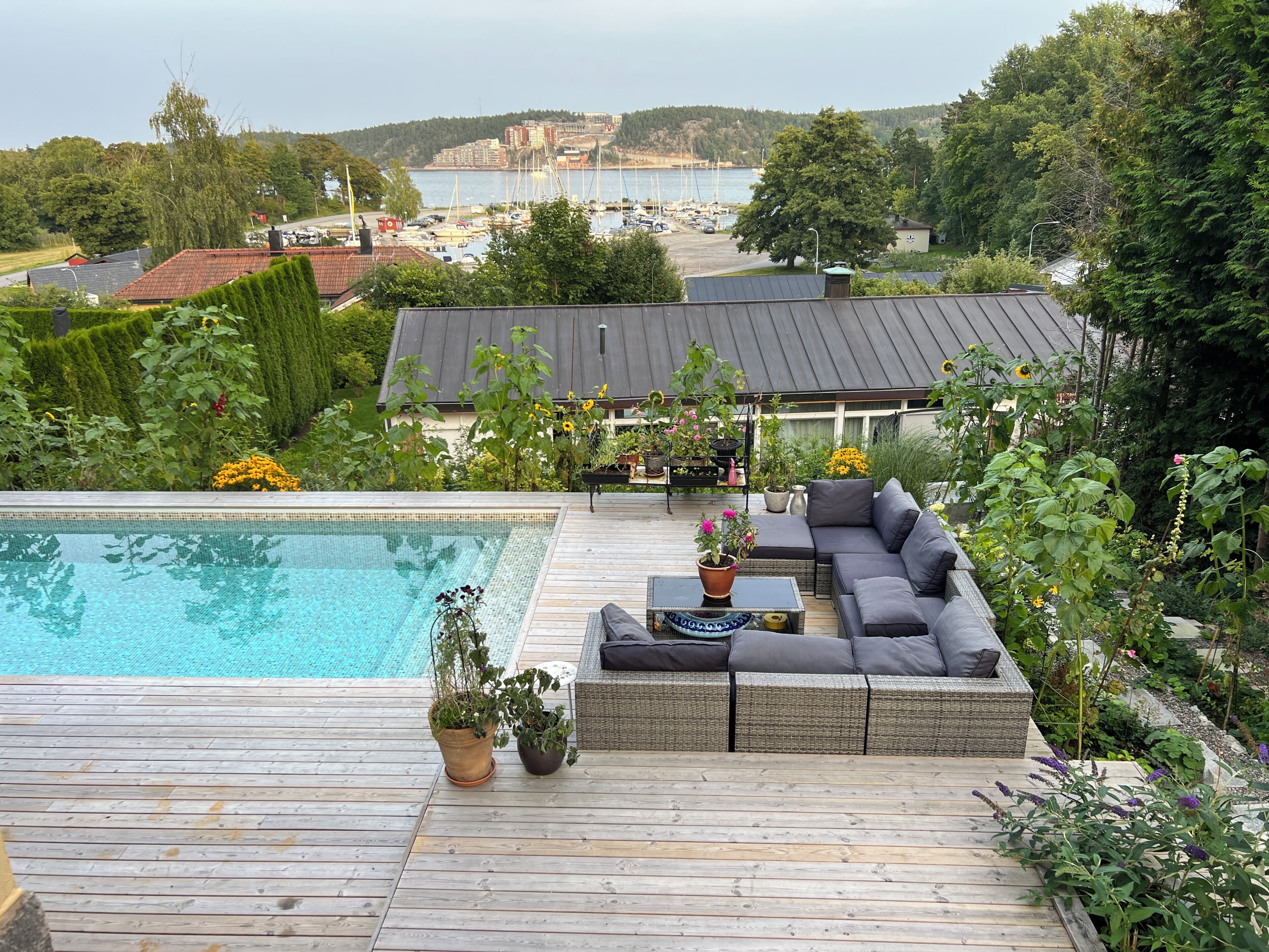 A wooden deck with a pool, outdoor seating, and potted plants.