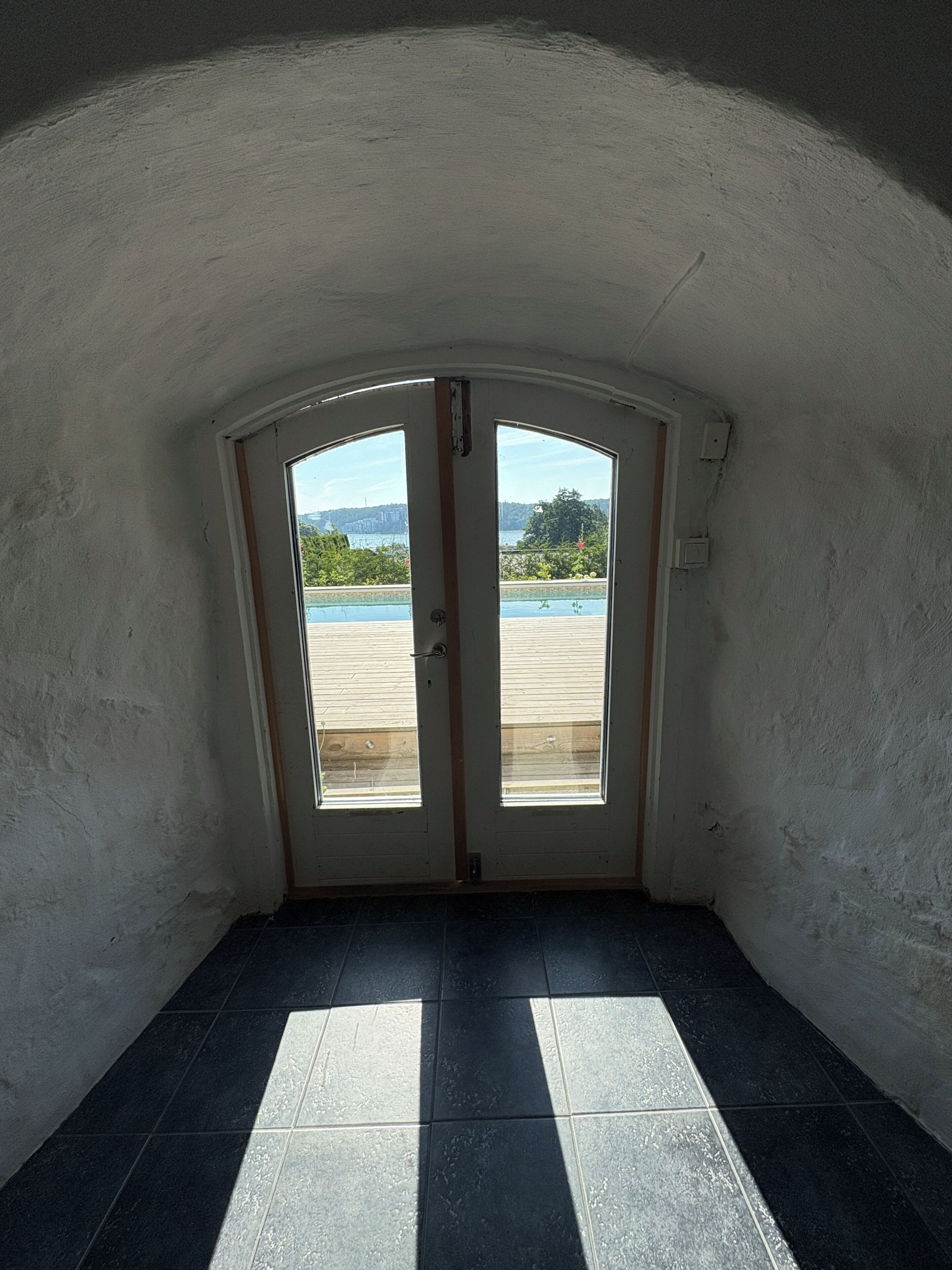 A room with a view of a swimming pool and a building in the distance.