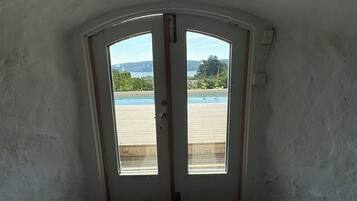 A room with a view of a swimming pool and a building in the distance.