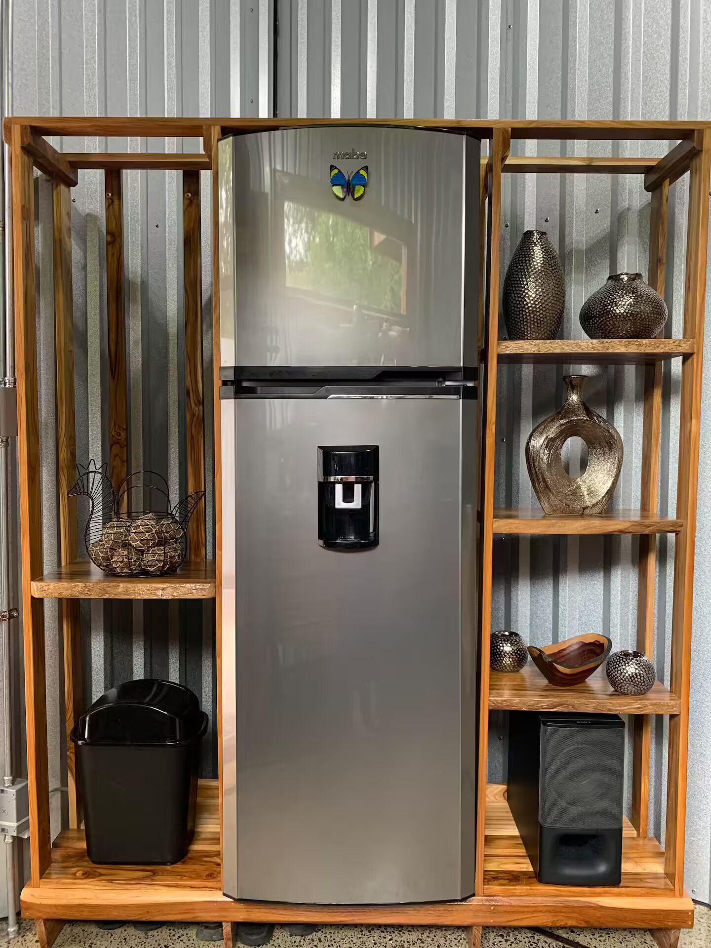 A modern kitchen with a built-in stainless steel refrigerator, wooden shelves, and various kitchenware.