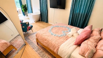 Une chambre à coucher avec un lit, une télévision, une salle de bain et un miroir.