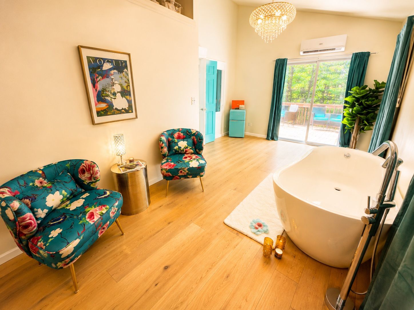 Un baño moderno con una bañera independiente, una pequeña mesa redonda con una lámpara y dos sillones con motivos florales.