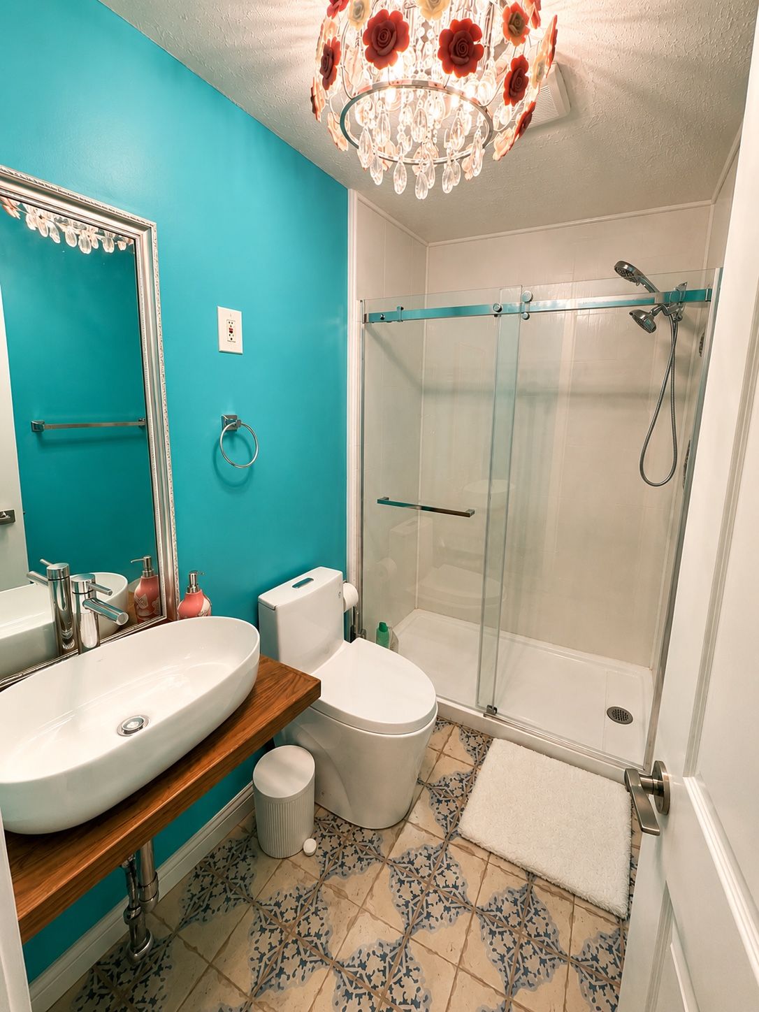 A bathroom with a large mirror, a sink, a toilet, and a glass-enclosed shower.
