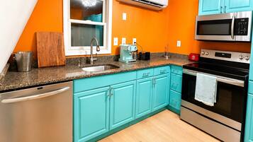 Une cuisine avec des meubles de couleur turquoise, un lave-vaisselle, un four à micro-ondes et un four traditionnel.