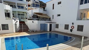 A swimming pool surrounded by a white building with balconies and a tiled deck. - Apartment in Los Cristianos - Ocean View (Arona)