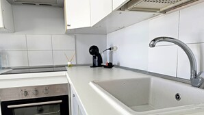 A kitchen with a white countertop, a stainless steel sink, and a built-in oven. - Apartment in Los Cristianos - Ocean View (Arona)