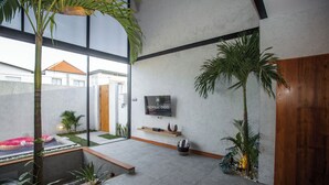 Un interior moderno con un ventanal grande, una puerta de madera y un televisor montado en la pared.