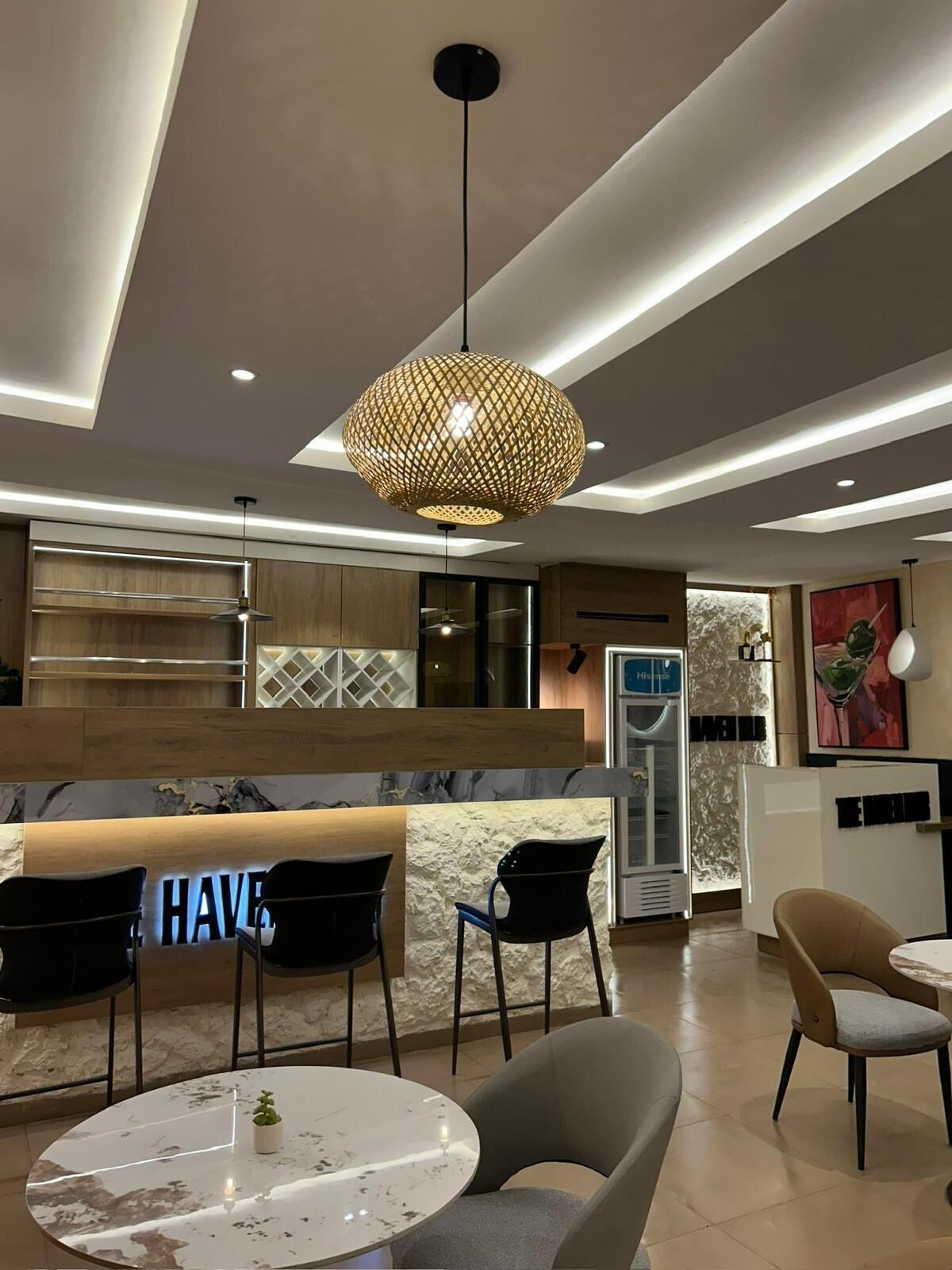 A modern interior with a reception desk, seating area, and a kitchen in the background.