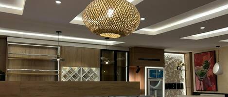 A modern interior with a reception desk, seating area, and a kitchen in the background.