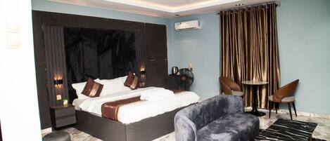 A modern bedroom with a large bed, a sofa, a small table, and a chair.