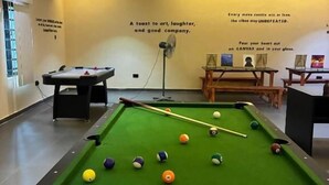 A pool table with balls, a fan, and a table with a painting. - The Haven Hub (Abeokuta)