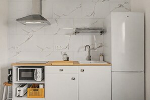 A compact kitchen with a built-in microwave, toaster, and a white refrigerator.