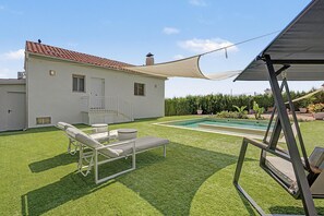 Une propriété résidentielle dotée d’une piscine, d’un patio couvert et d’une pelouse bien entretenue.
