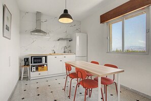 A compact kitchen with a dining area, a microwave, a toaster, and a refrigerator.