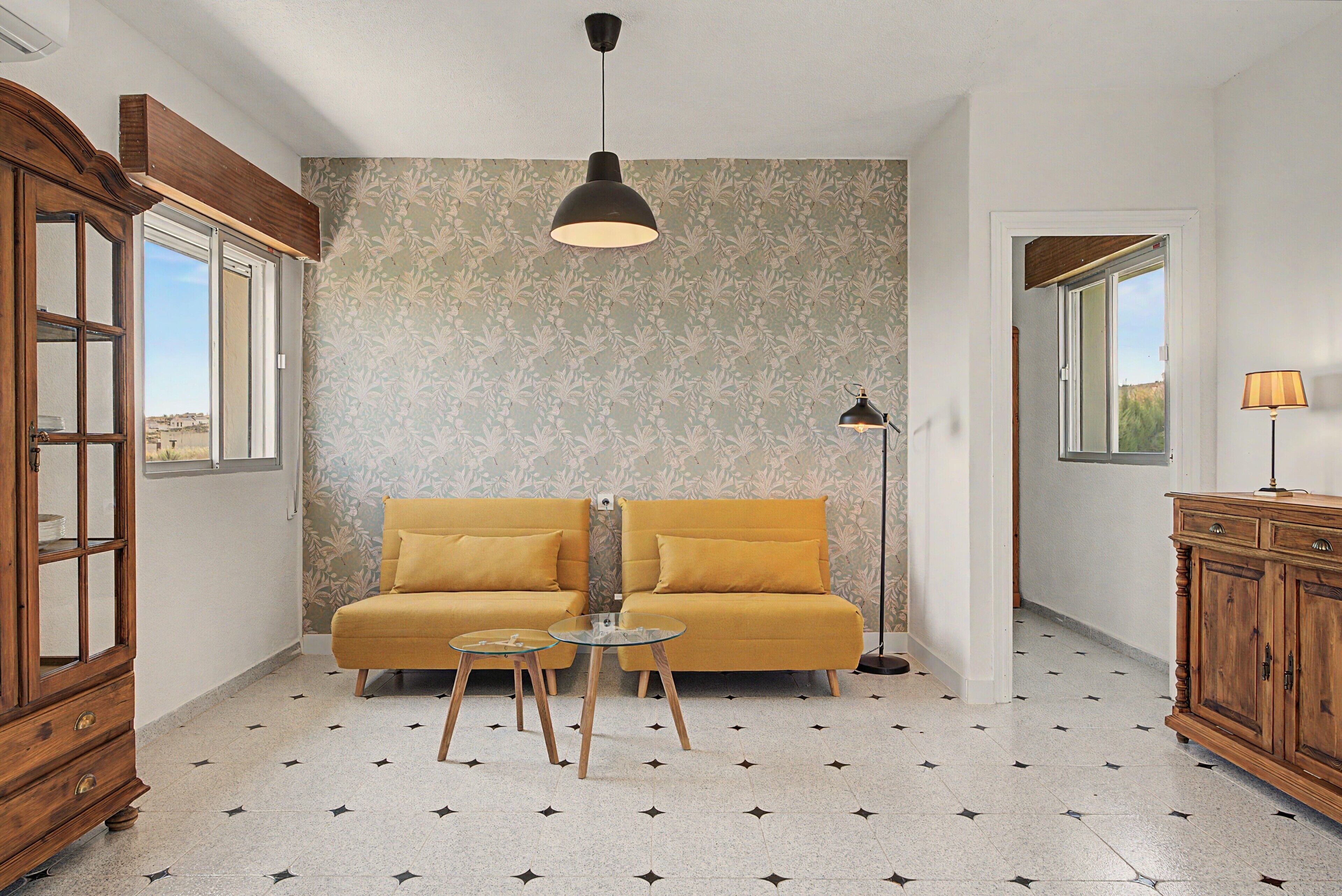 Una habitación con sofá, una mesita, un armario y una pared con diseño.