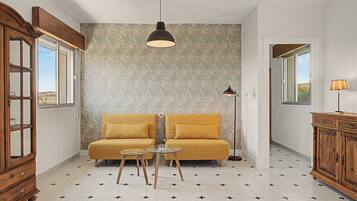 Una habitación con sofá, una mesita, un armario y una pared con diseño.