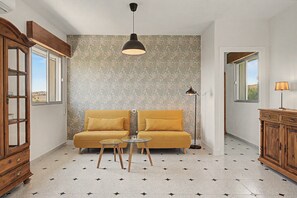 A room with a sofa, a small table, a cabinet, and a patterned wall.