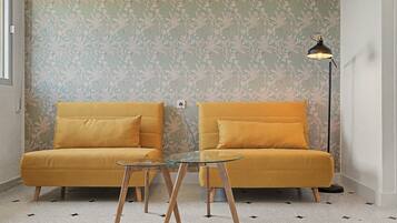 A room with two mustard-colored sofas, a glass coffee table, and a floor lamp.