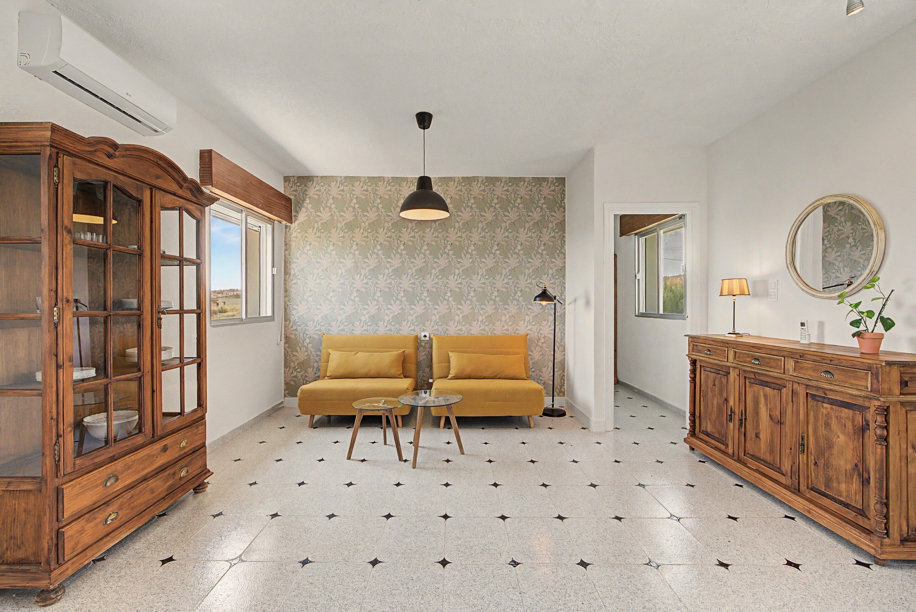 Una habitación con un sofá, un armario de madera, una lámpara de pie y un espejo en la pared.