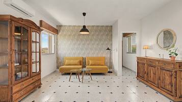 Una habitación con un sofá, un armario de madera, una lámpara de pie y un espejo en la pared.