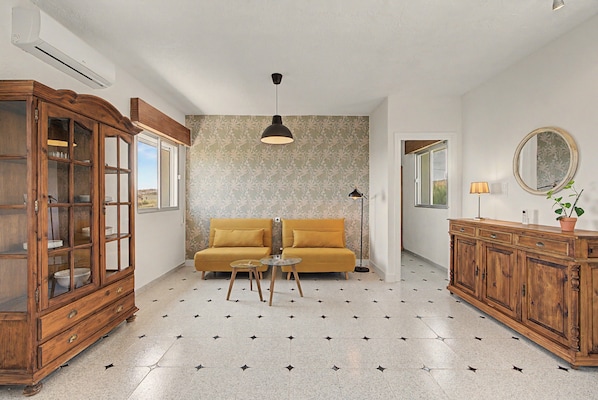 A room with a sofa, a wooden cabinet, a floor lamp, and a mirror on the wall.