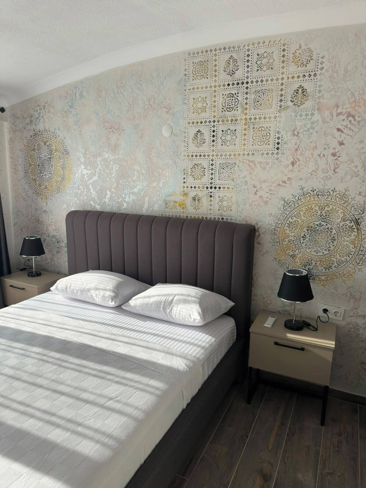 Un dormitorio con cama, dos mesitas de noche, un velador y un techo con diseño, además de un ventilador de techo.
