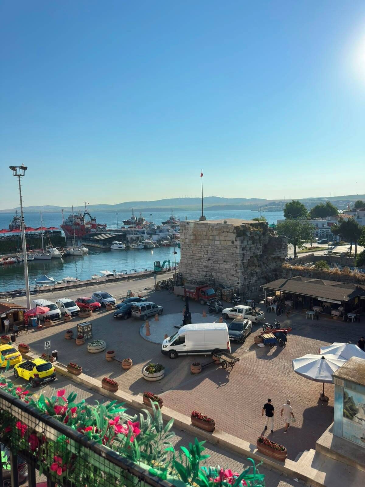 Un port avec des bateaux, un fourgon blanc et une construction en pierre.