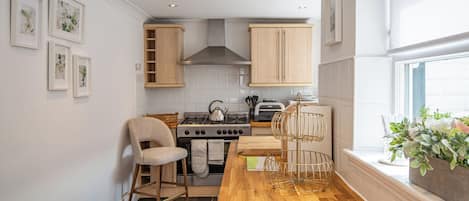 A kitchen with wooden cabinets, a gas stove, a sink, and a window with plants.