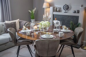 Mesa de comedor lista con platos blancos, tazas y cubiertos, rodeada de sillas de cuero.