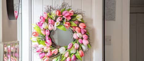 A white door with a wreath of pink and white flowers.