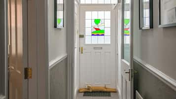 A hallway leading to a door with a doormat and a dog lying on it.