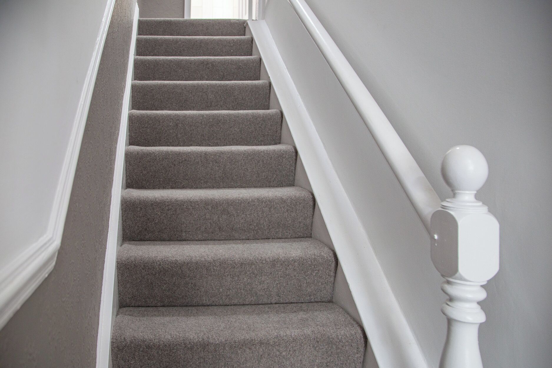 Una escalera con peldaños alfombrados y balaustres blancos.