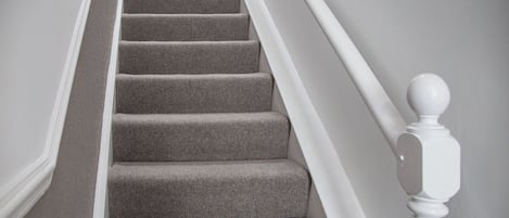 A staircase with carpeted steps and white balusters.