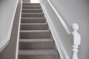 Eine Treppe mit Teppichstufen und weißen Spindeln.