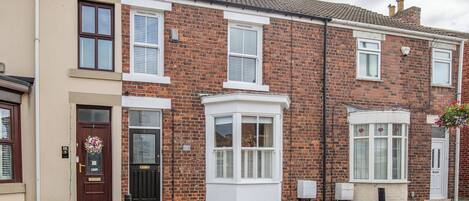A row of terraced houses with distinct front doors, windows, and a bay window.