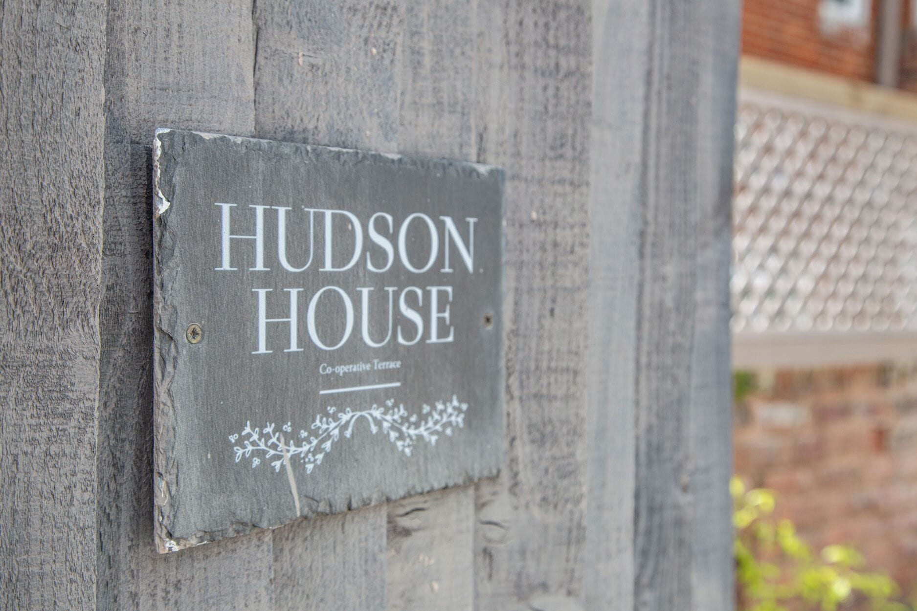 A sign on a wooden wall that reads 'HUDSON HOUSE Co-operative Terrace.'